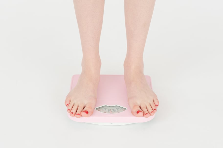 Woman checking weight on scales in studio